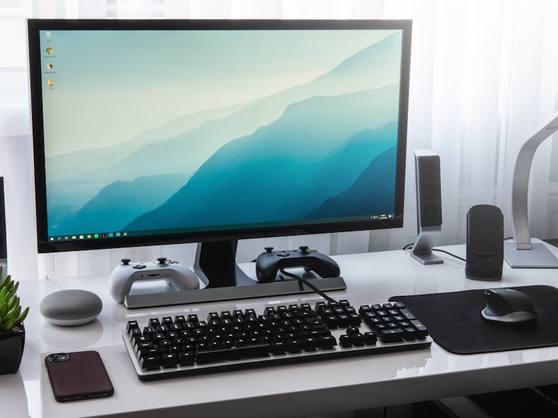 A desktop monitor and keyboard set up on a clean white desk.